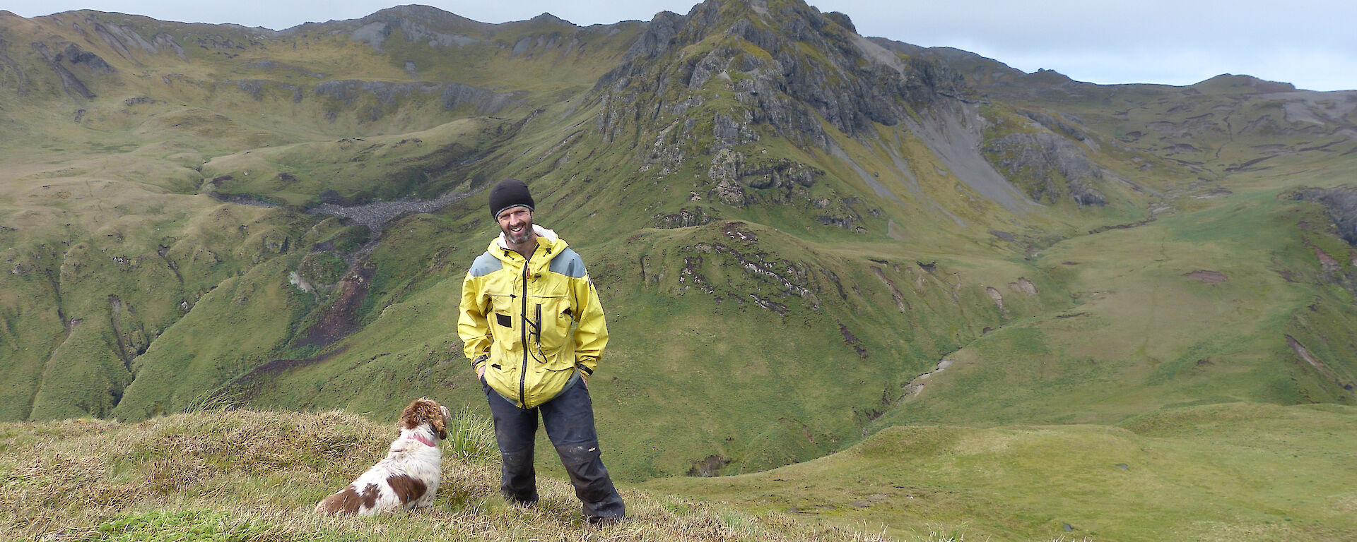 Expeditioner and his dog posing for the camera, mountains in the background