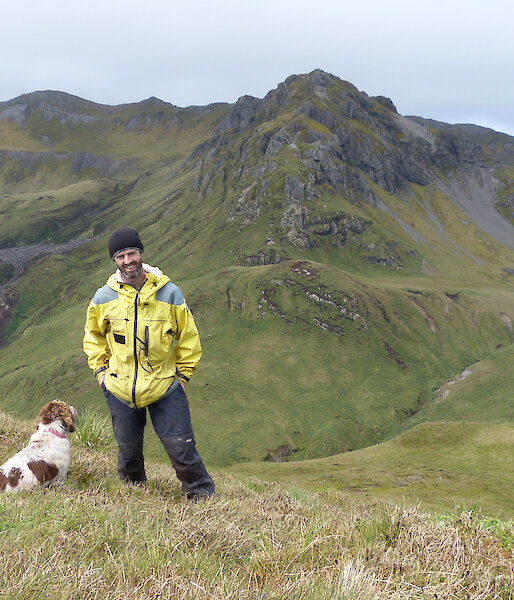 Expeditioner and his dog posing for the camera, mountains in the background