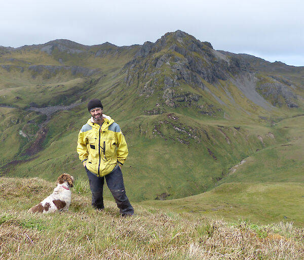 Expeditioner and his dog posing for the camera, mountains in the background