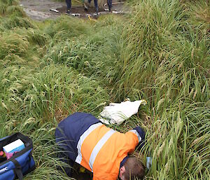 Close up on one expeditioner, three expeditioners in background filling in a hole