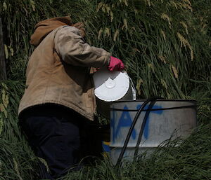 Expeditioner pouring contents of a bucket into a drum