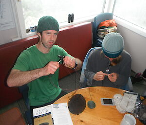 Male expeditioner wearing a concerned look on his face finding it hard to learn to knit