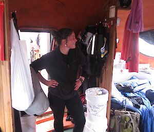 Female expeditioner modeling black thermal trousers and top in a hut