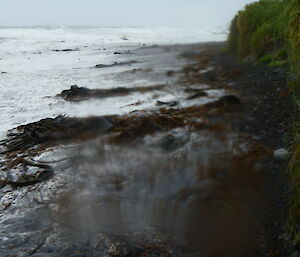 Large waves washing up covering the entire sandy beach