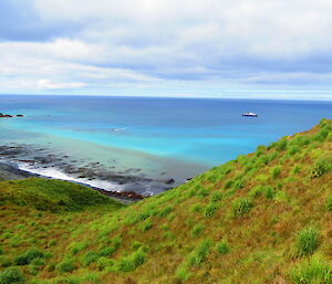 View of a tourist vessel out at sea light blue water and green hills