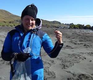 Expeditioner in blue jacket holding a drum seal in her hand