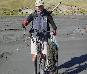 Expeditioner on the beach holding a large knotted old rope