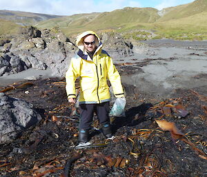 Expeditioner standing in the middle of large mound of kelp in the beach