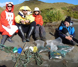 Four expeditioners standing next to all the rubbish they collected on the beach