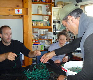 Expeditioners in a hut picking up the rubbish they found on the beach