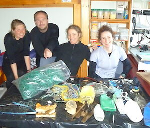 Four expeditioners in a hut with a large pile of rubbish collected from the beach