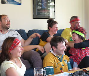 Eight expeditioners in an office looking towards a TV screen, all very excited