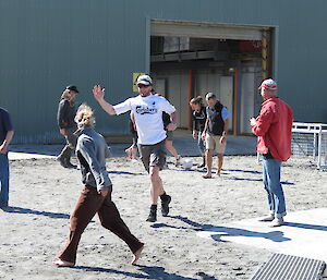 Two teams of expeditioners playing soccer on the sand, in front of station buildings