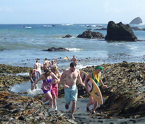 Nine runners coming out of the water, running between large kelp beds