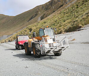 Tractor driving on the beach followed by a small red ute