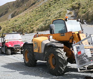 Small red ute following a larger tractor on the sand