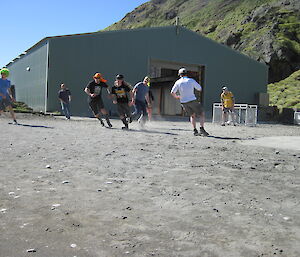 Expeditioners moving fast and kicking up dust whilst playing soccer