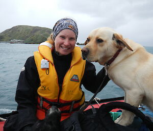 Female expeditioner with her golden labrador dog sitting in an inflatable boat