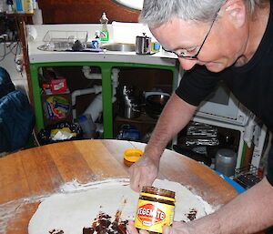 Expeditioner with a jar of vegemite in his hand spreading if on dough