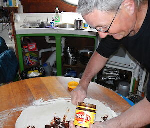 Expeditioner with a jar of vegemite in his hand spreading if on dough