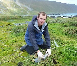Expeditioner kneeling down collecting soil samples