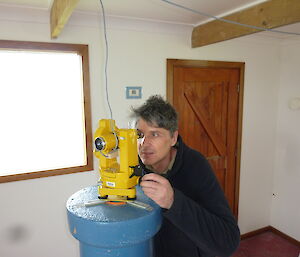 Male expeditioner looking through a yellow instrument