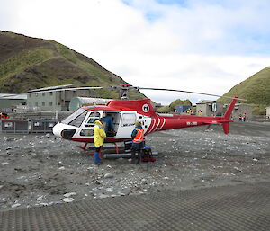 Helicopter landed with three people standing next to it