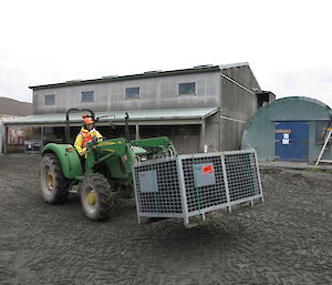 Male expeditioner driving a tractor carrying large pallet