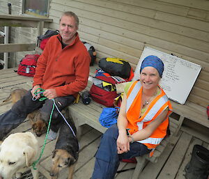 Two expeditioners each with a dog sitting on a bench