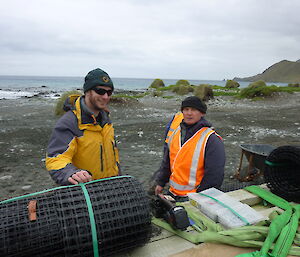 Two male expeditioners standing next to wire mesh