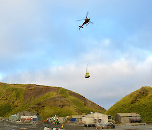 A red and white helicopter carrying a suspended load