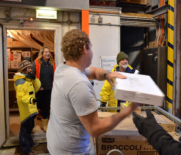 A team of expeditioners unloading boxes into a store room