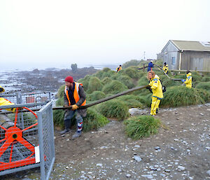 Expeditioners pulling a large green fuel hose on a beach