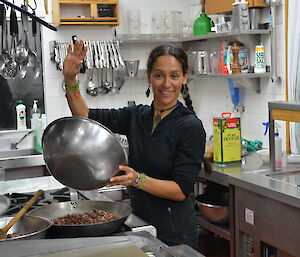 Patty at work in the kitchen, adding an ingredient to a frying pan full of beans