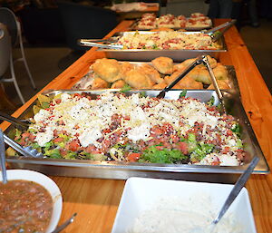 A long table with several platters piled with mexican style food