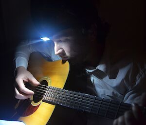 During Earth Hour — a close up of Aaron, wearing a head torch, strumming away on his guitar