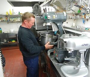 Chris standing in front of the big mixer in the kitchen, trying to fit the large mixing bowl into its slot