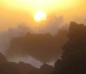 Sunset through the surf and rugged coastal rocks on the west coast