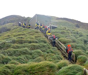 Team two, all climbing up the steep steps on the grassy slope on the right their is a hut