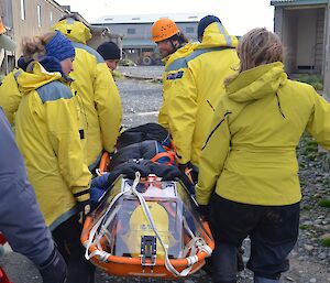 Rescue team members carrying a male expeditioner into base