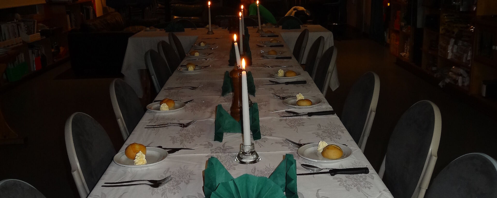 Table set for dinner white table cloth candles a side plate with a bread roll and butter