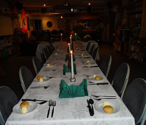 Table set for dinner white table cloth candles a side plate with a bread roll and butter