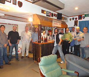 a photo of some of the team at macquarie island all are standing arount a bar, there are a few chairs in the front