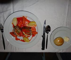 a vegetarian dish next to it is a side plate with a bread roll and butter and cuttlery is set
