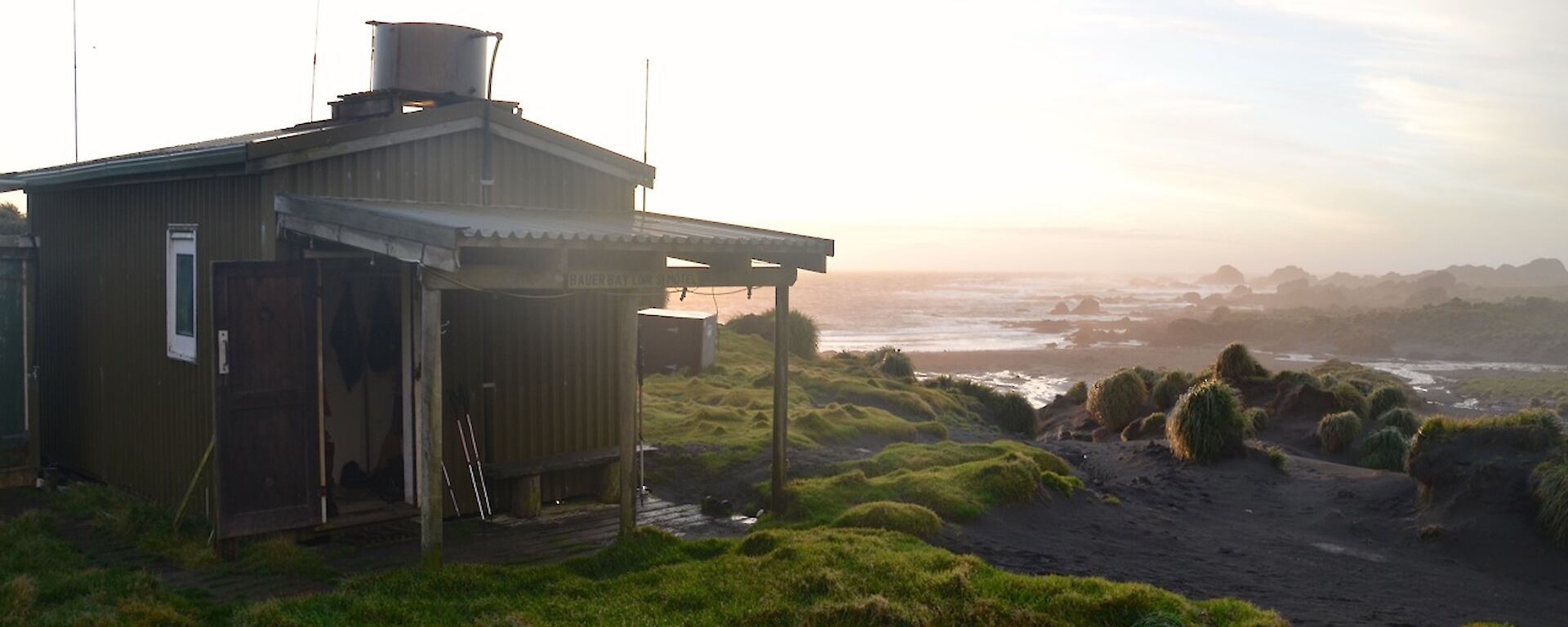Bauer Bay hut at sunset with the ocean and Boiler Rocks in the right background