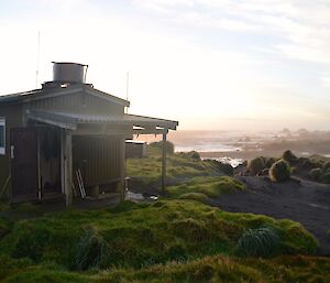 Bauer Bay hut at sunset with the ocean and Boiler Rocks in the right background