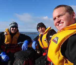 Aaron Tony and Josh sitting in the boat blue sky behind them