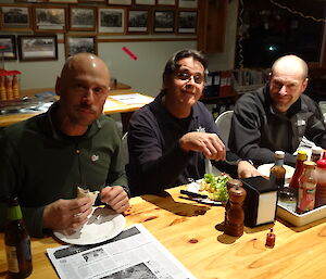 Marty, Barry and Mark sitting at the table eating kebabs a tray of sauces on the right