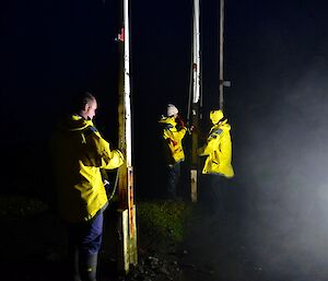 Three Expeditioners fixing flags to flag poles