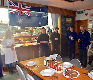 Team members toasting on Anzac day in the mess in front of Australian flag